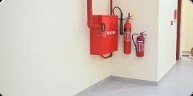 Fire hose reel cabinet and extinguishers on a wall